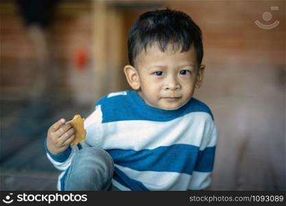 Portrait of Asian boy eating the cookie in home, family concept