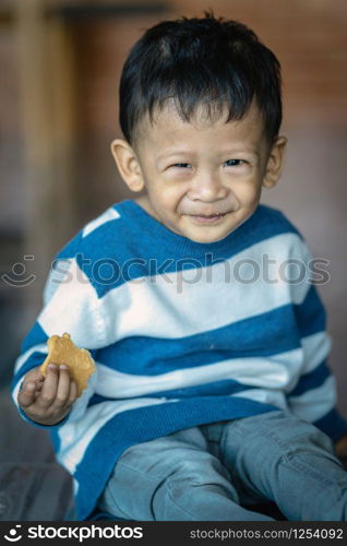 Portrait of Asian boy eating the cookie in home, family concept