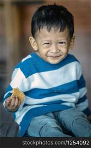 Portrait of Asian boy eating the cookie in home, family concept