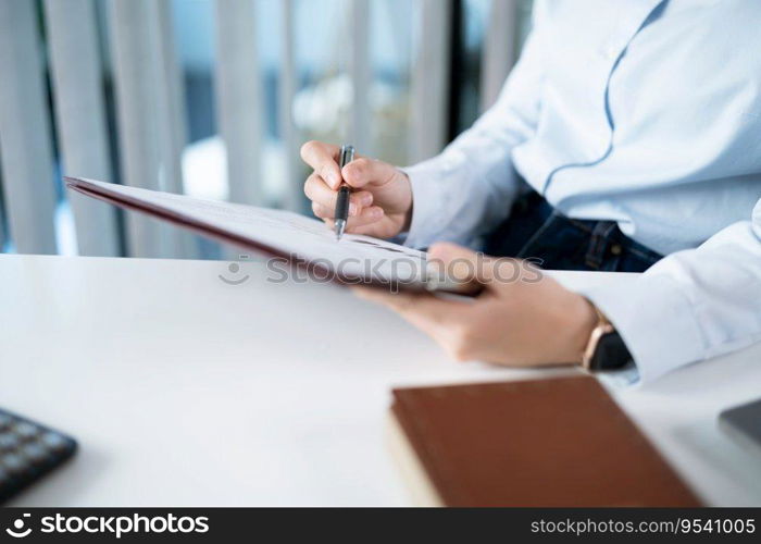 Portrait of  Asian Business woman working from office taking reading and writing notes in note pad working on laptop computer  in her workstation.