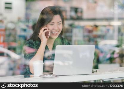 Portrait of asian businesswoman in casual suit talking and working with technology laptop in happiness action at the desk beside the glass in modern office, Business owner and entrepreneur concept