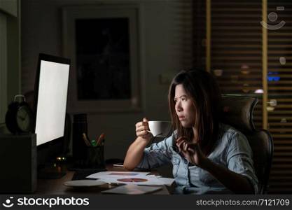 Portrait of Asian Businesswoman sitting and working hard on the table with front of computer desktop in workplace at late with serious action, Work hard and too late concept