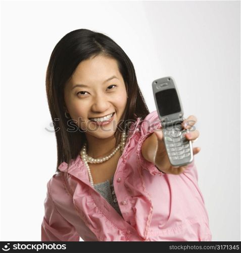 Portrait of Asian Chinese mid-adult female smiling and holding out cell phone towards viewer.