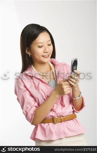 Portrait of Asian Chinese mid-adult female smiling and text messaging on cell phone.