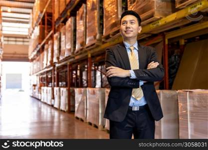 Portrait of asian confidence businessman investor stand in large factory and distribution warehouse environment. Business owner and investment concept.