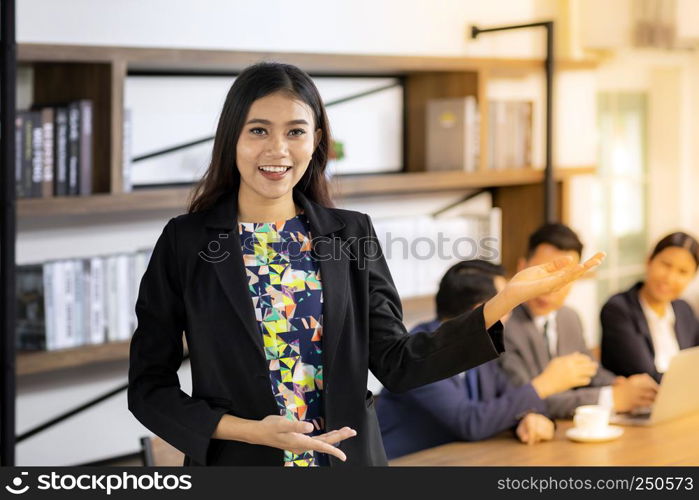 Portrait of asian confidence Businesswoman stand in front of table in meeting room in cafe with business team in background using for coporate background work