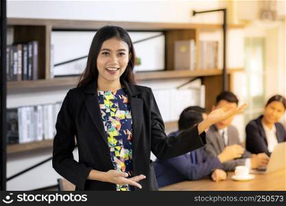 Portrait of asian confidence Businesswoman stand in front of table in meeting room in cafe with business team in background using for coporate background work