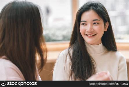 Portrait of Asian cute woman smiling and talking to her friend in coffee shop. Lifestyle Concept.