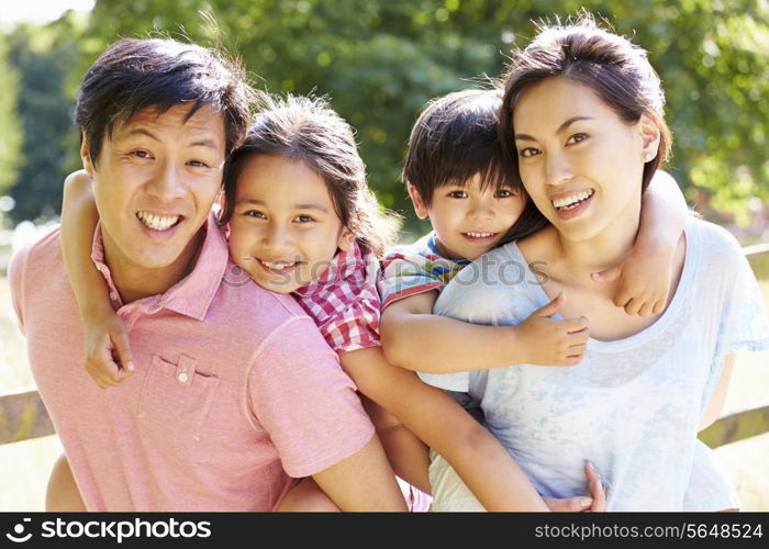 Portrait Of Asian Family Enjoying Walk In Summer Countryside