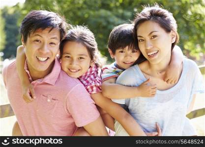 Portrait Of Asian Family Enjoying Walk In Summer Countryside