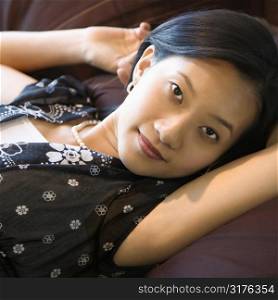 Portrait of Asian female lying on bed looking at viewer.