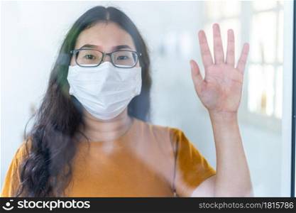 Portrait of asian female wears hygiene protective mask in orange dress doing a stop gesture with protective gloves in hands while looking at camera in the consultation,Concept of COVID-19 virus