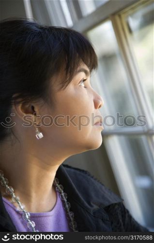 Portrait of Asian Filipino woman gazing out window.