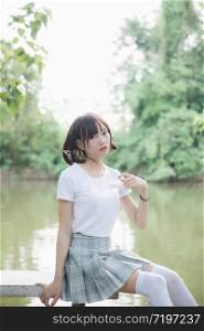 portrait of asian girl with white shirt and skirt sitting in outdoor nature vintage film style
