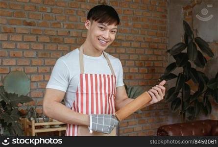 Portrait of Asian handsome man cooking in kitchen room at home. Lifestyle Concept.