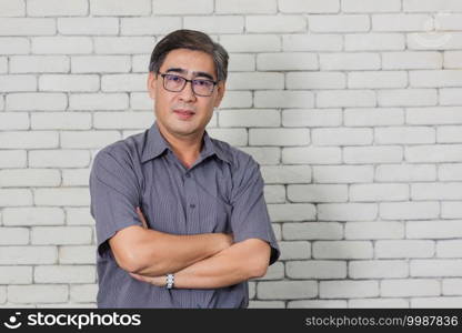 Portrait of Asian handsome senior elderly man wear eyeglasses on white brick wall background. Old man standing golden age grandfather healthcare cheerful lifestyle