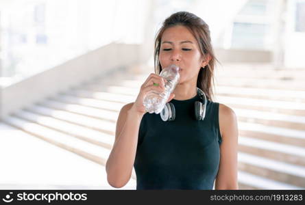 Portrait of Asian healthy and sportive woman wearing sport bra and drinking water. Sport and Lifestyle Concept.