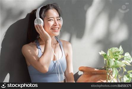 Portrait of asian healthy and sportive woman wearing sport bra and listen music at cozy home.