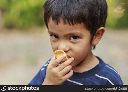 Portrait of Asian little boy eating crisp rice outdoor