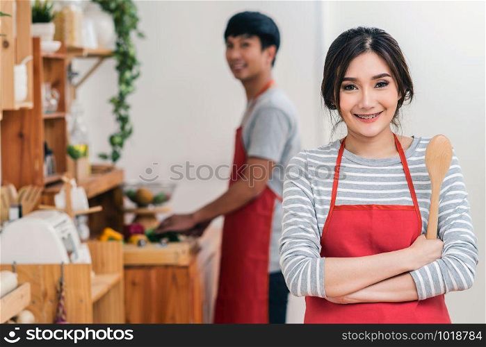 Portrait of Asian Lover or Couple cooking with smiling action in the kitchen room at the modern house, Couple and life style concept.