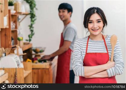 Portrait of Asian Lover or Couple cooking with smiling action in the kitchen room at the modern house, Couple and life style concept.