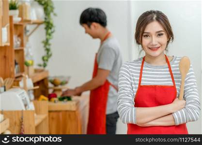 Portrait of Asian Lover or Couple cooking with smiling action in the kitchen room at the modern house, Couple and life style, kitchen and making food concept