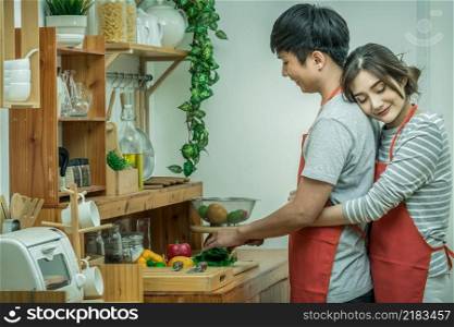 Portrait of Asian Lover or Couple hugging and cooking with smiling action in the kitchen room at the modern house, Couple and life style concept.