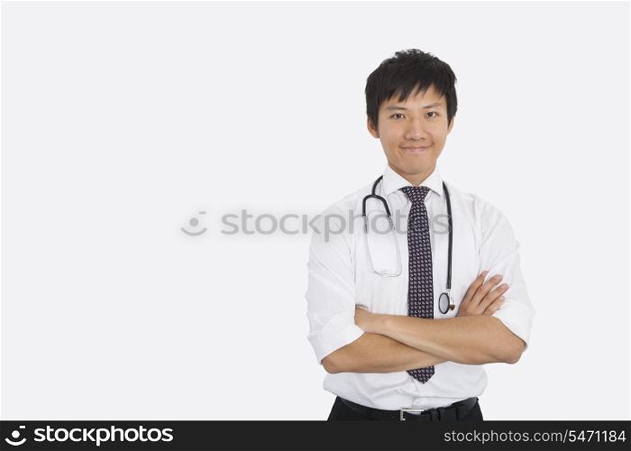 Portrait of Asian male doctor with arms crossed over white background