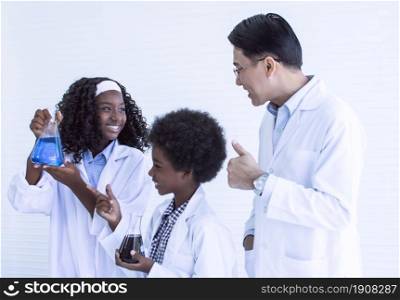 Portrait of asian male teacher and african black boy and girl studying science in classroom at school. Education and Diversity Concept.