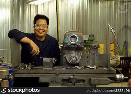 Portrait of Asian man in machine shop.