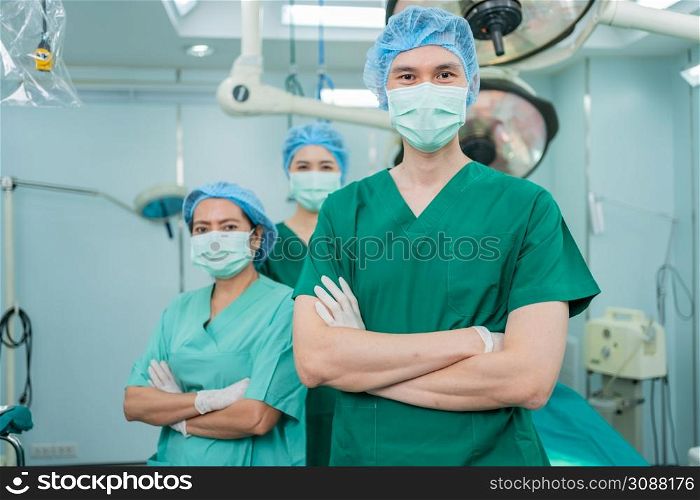 Portrait of Asian men surgeon and nurse with medical mask standing with arms crossed in operation theater at a hospital. Team of Professional surgeons. Healthcare, emergency medical service concept