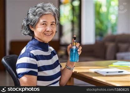Portrait of Asian old man woman showing hand sanitizer by pumping alcohol gel and washing before working in work from home period,coronavirus or covid19 outbreak,social distancing and responsibility