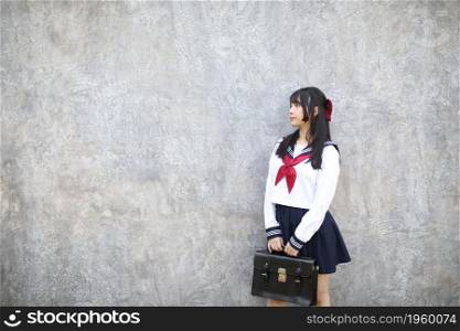 Portrait of Asian schoolgirl with grey background