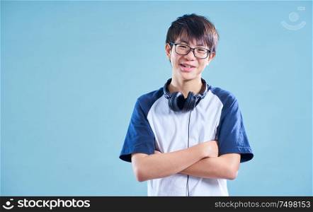 Portrait of Asian teenage smiling boy in studio with light blue background . Music headphone concept .