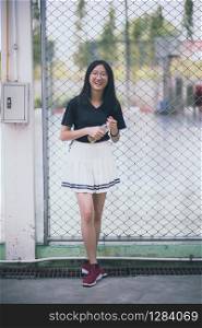 portrait of asian teenager wearing white short skirt laughing with happiness emotion