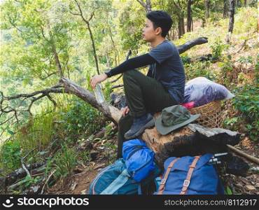 Portrait of Asian traveler man with backpack on a hiking trip in forest.