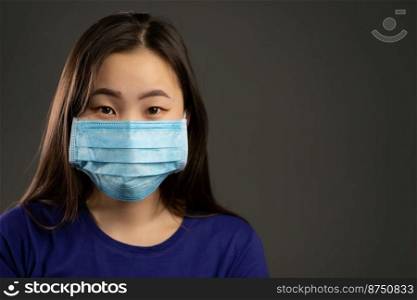 Portrait of asian woman in face protective mask isolated on grey studio background. City air pollution, Coronavirus, epidemic 2020, illness concept. Portrait of asian woman in face protective mask isolated on grey studio background. Copy space, City air pollution, Coronavirus, epidemic 2020, illness concept.