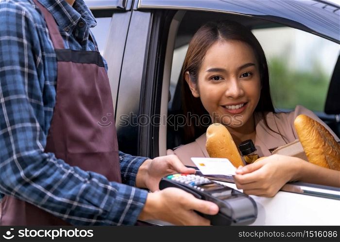 Portrait of asian woman make mobile payment contactless technology for online grocery ordering and drive thru service. Drive through and food online is new normal popular after coronavirus pandemic.