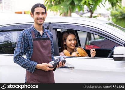 Portrait of asian woman make mobile payment contactless technology for online grocery ordering and drive thru service. Drive through and food online is new normal popular after coronavirus pandemic.
