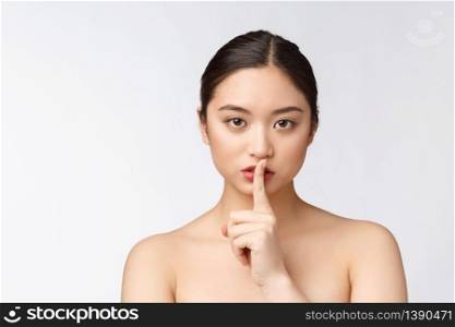 Portrait of asian woman making a hush gesture with finger on lips, isolated on white background.. Portrait of asian woman making a hush gesture with finger on lips, isolated on white background