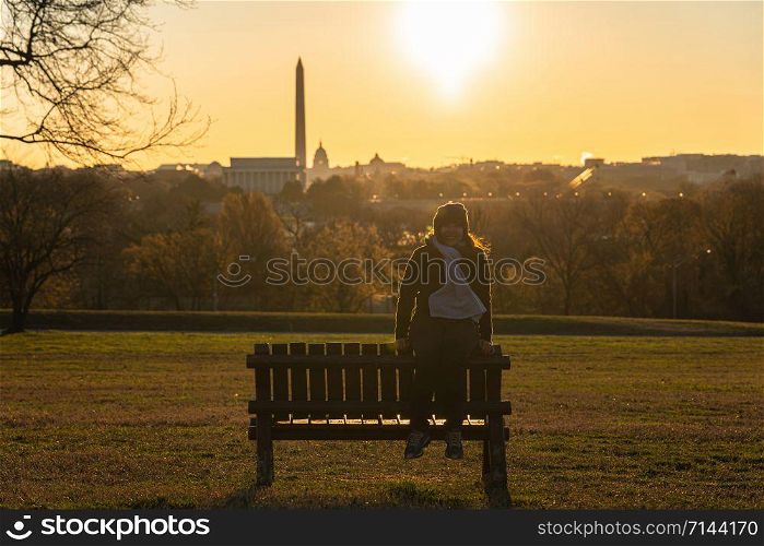 Portrait of asian woman tourist sitting over the Washington DC Landmark which can see United states Capitol, washington monument and lincoln memorial at the sunrise time, history and culture concept