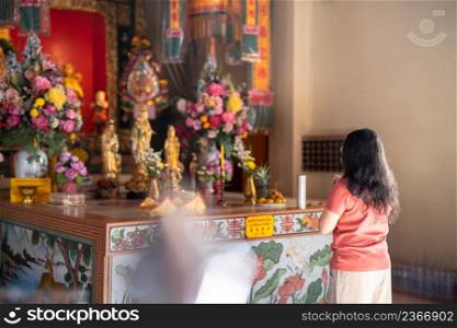 Portrait of asian woman traveler wear protective mask germs is holding joss sticks pray at Chinese buddhist temple or shrine in Thailand,Prevention of the spread of COVID-19 virus,Chinese New Year