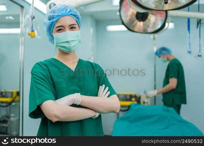 Portrait of Asian women surgeon and nurse with medical mask standing with arms crossed in operation theater at a hospital. Team of Professional surgeons. Healthcare, emergency medical service concept