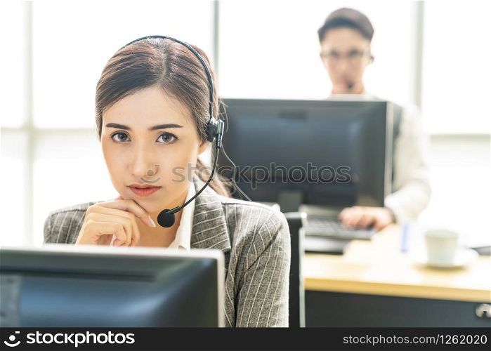 Portrait of Asian young adult friendly and confidence operator call centre with headsets in a call center as customer service and technical support.