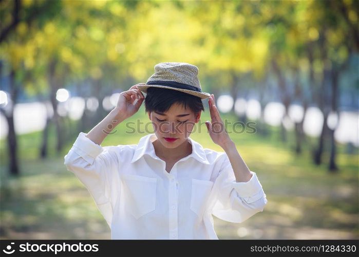 portrait of asian young beautiful woman wearing straw hat standing in summer flower blooming park relaxing emotion