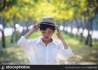 portrait of asian young beautiful woman wearing straw hat standing in summer flower blooming park relaxing emotion