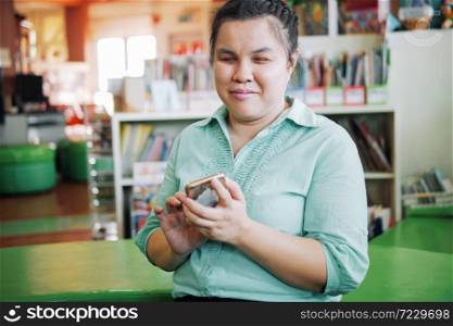 Portrait of Asian young blind woman using smart phone with voice accessibility for persons with disabilities in creative workplace