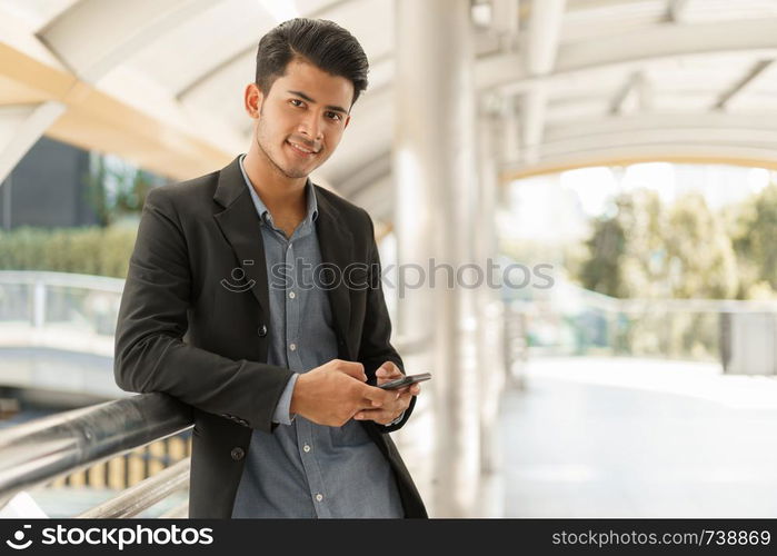 Portrait of asian young businessman standing at Outside Office. Young businessman wear suit smiling and looking at camera.