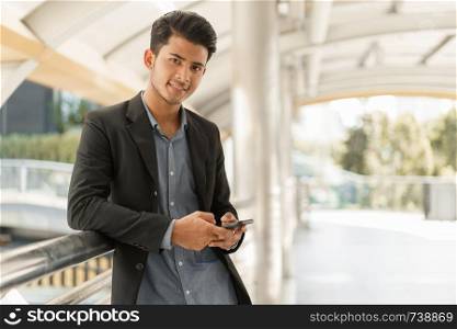 Portrait of asian young businessman standing at Outside Office. Young businessman wear suit smiling and looking at camera.