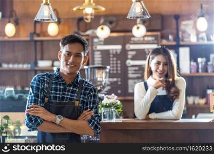 Portrait of Asian Young Small business owner with coffee shop in front of counter bar, entrepreneur and startup, preparing for service to customer in cafe store and restaurant,business partner concept